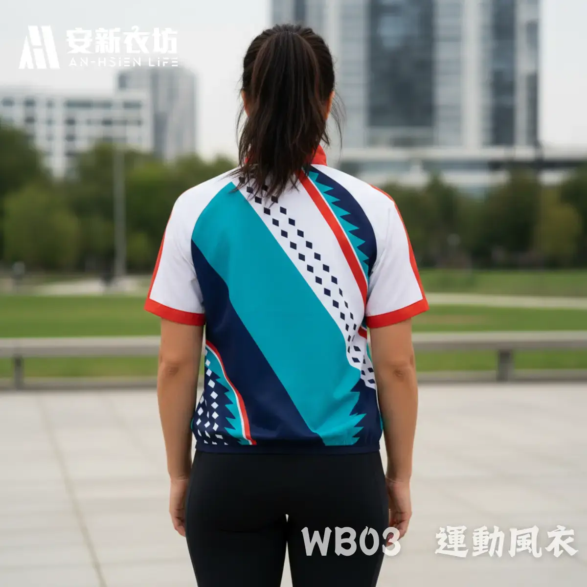 安新衣坊WB03運動風衣女版專業實穿照背面視角。女模特兒背對鏡頭站立於都會廣場，展示白、藍綠與深藍斜向幾何撞色短袖防風外套。背部圖騰與正面完美連貫，紅色小立領設計展現俐落修身的女性運動休閒風格。