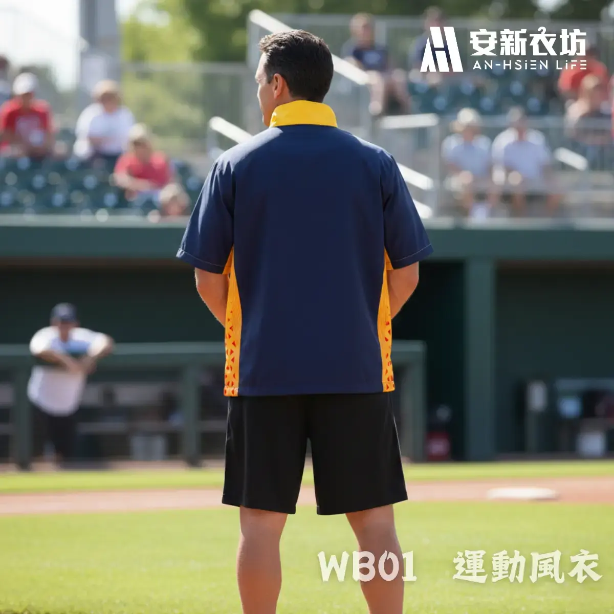 運動風衣WB01 安新衣坊WB01運動風衣男版專業實穿照背面視角。男模特兒背對鏡頭站立於棒球場,展示深藍與黃橘拼接短袖防風外套的背面俐落剪裁。背部提供大面積平整空間,適合客製化球隊Logo、專屬背號與姓名。