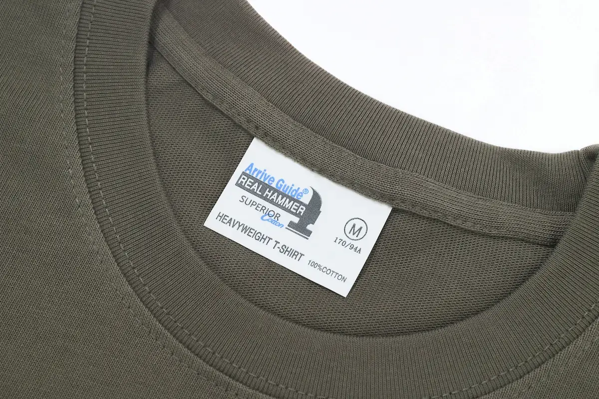 Arrive Guide AG28000 重磅 T 恤領口細節，展示 21 支雙紗緊密賽洛紡工藝與 100% 精梳棉領標，呈現領口雙層走線的紮實做工。