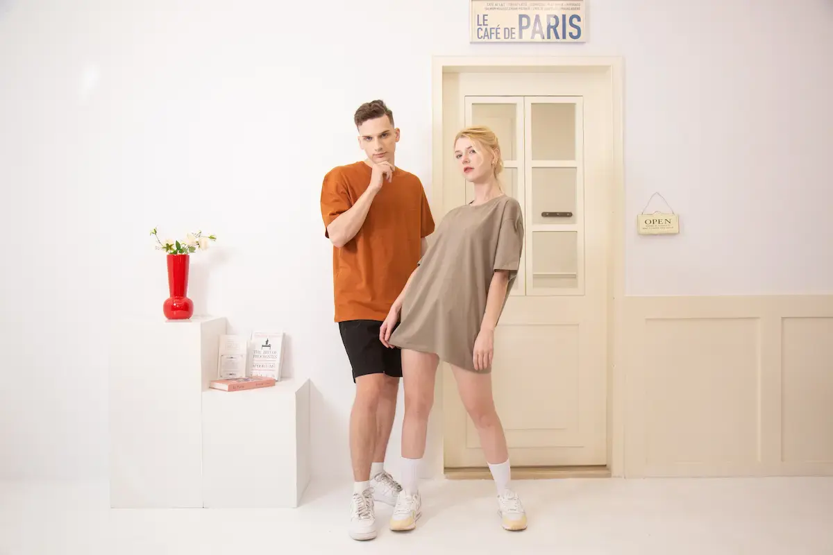 ARRIVE GUIDE AG18000頂級精梳棉T恤 一男一女模特兒穿著 AG18000 頂級精梳棉圓領 T 恤,分別展示焦糖色與大象灰的寬鬆穿搭效果,呈現韓系簡約風格。