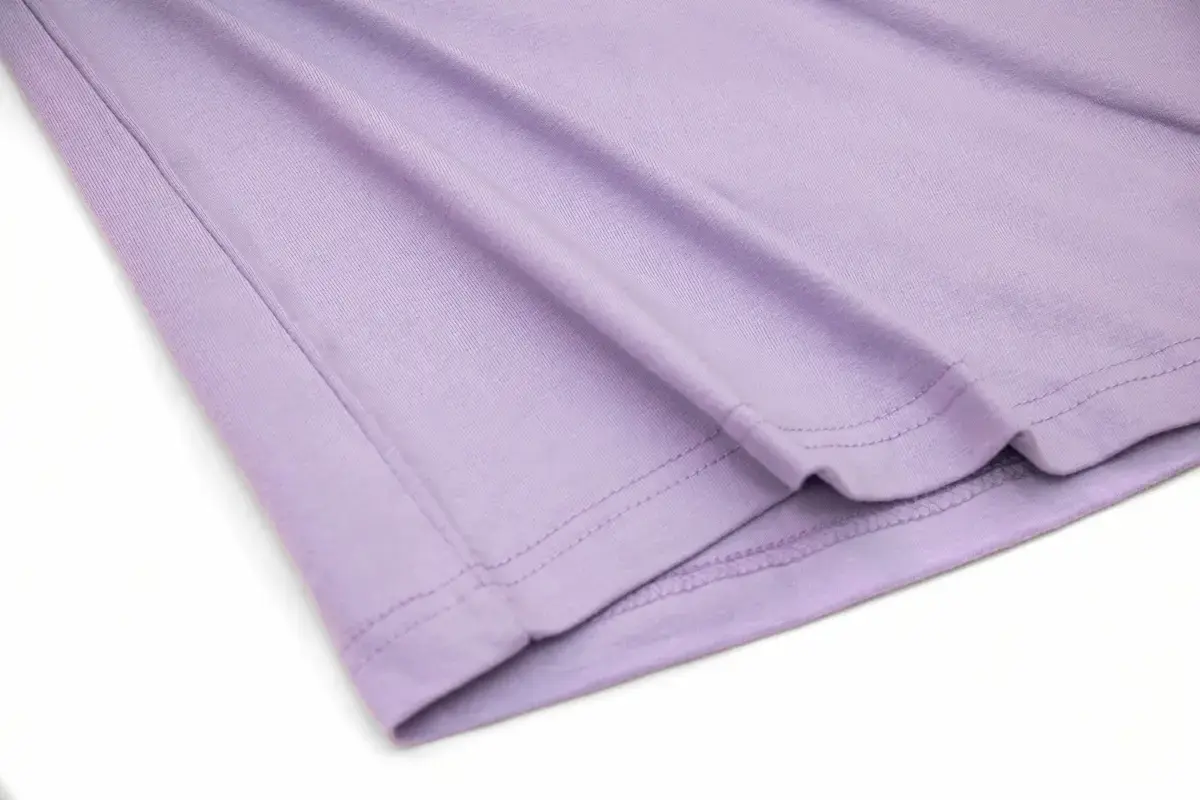 ARRIVE GUIDE AG18000頂級精梳棉T恤 AG18000 薰衣草紫色 T 恤的下擺細節特寫,展示平整工整的雙針車縫線工藝與高密度精梳棉布料。