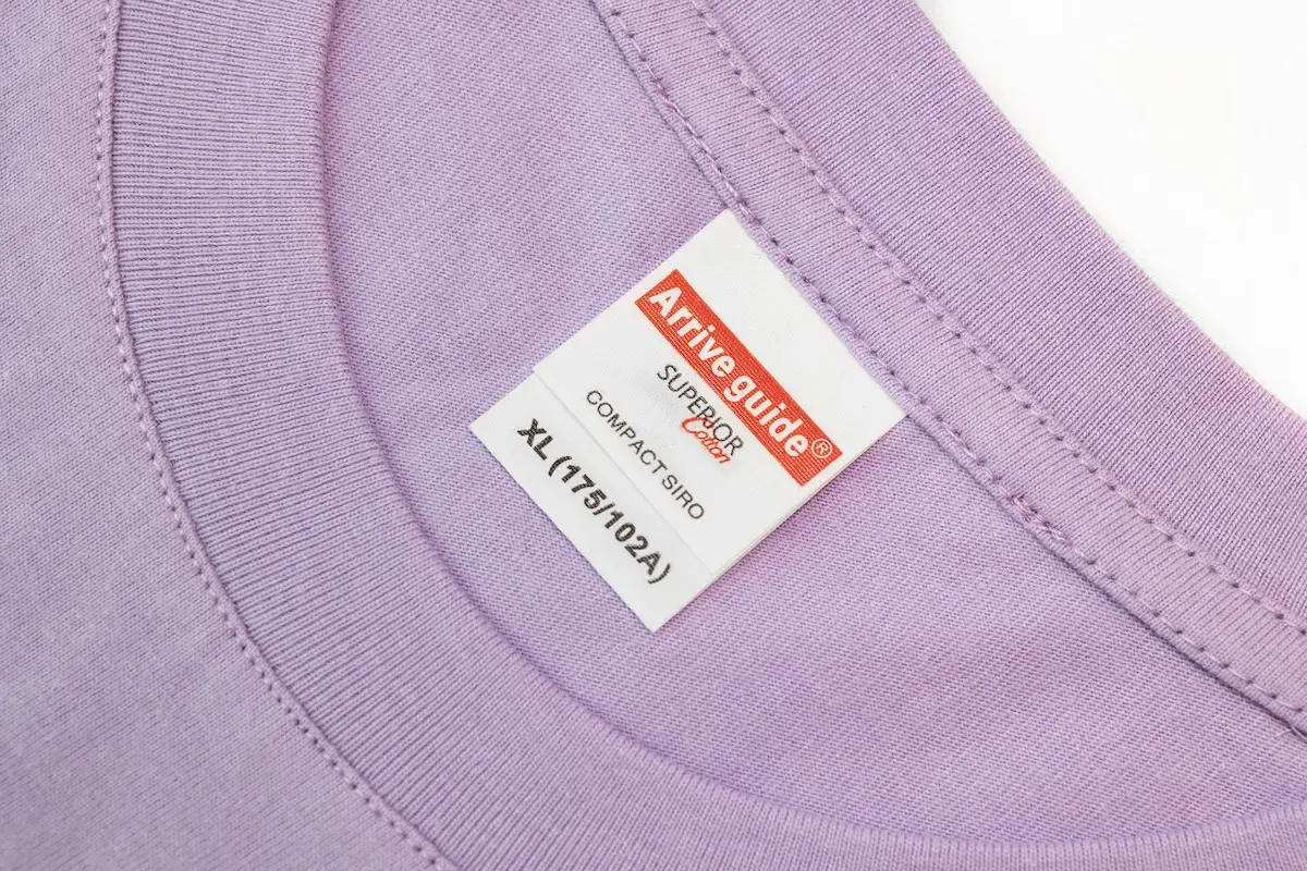 ARRIVE GUIDE AG18000頂級精梳棉T恤 ArriveGuide AG18000 薰衣草色 T 恤領口近照,展示 COMPACT SIRO 精梳棉標籤與領口緊密的二針加強縫線,確保領口耐洗不易變形。