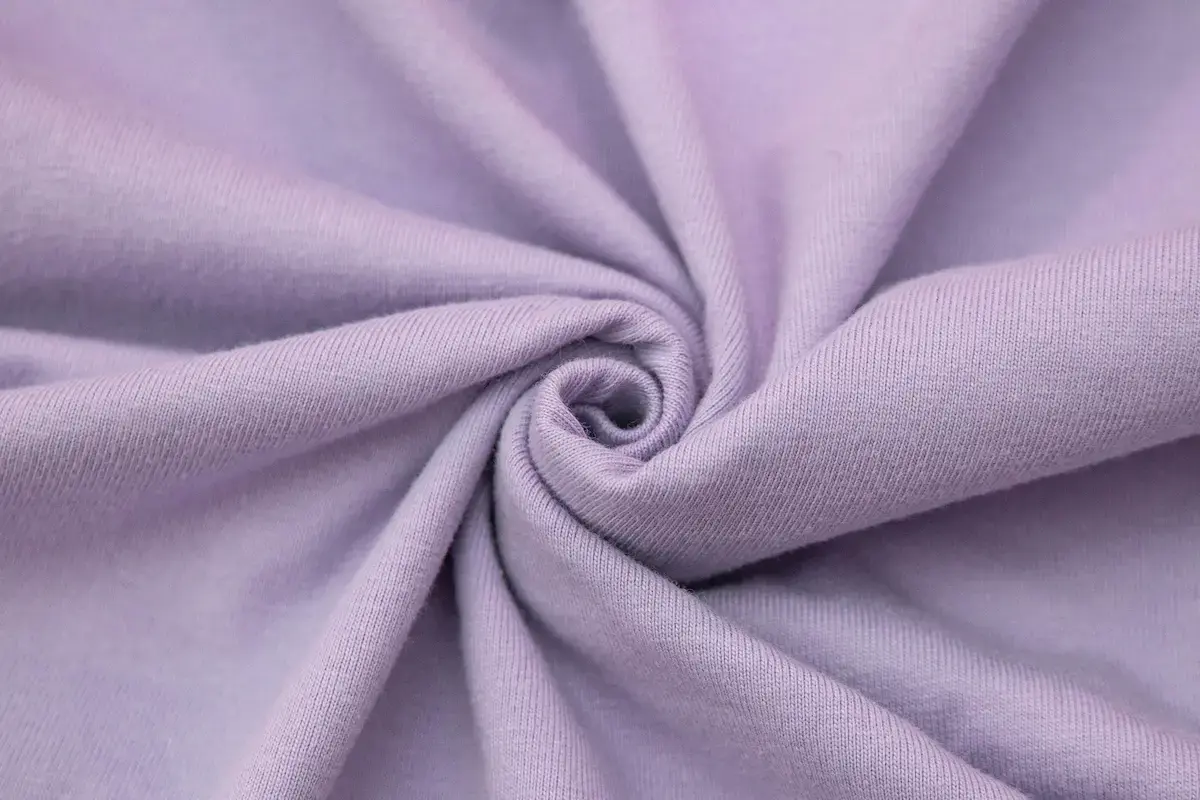 ARRIVE GUIDE AG18000頂級精梳棉T恤 AG18000 頂級精梳棉 T 恤的面料特寫,展示薰衣草色布料細緻平整的紋理與柔軟紮實的織法,呈現無毛躁的高質感表面。